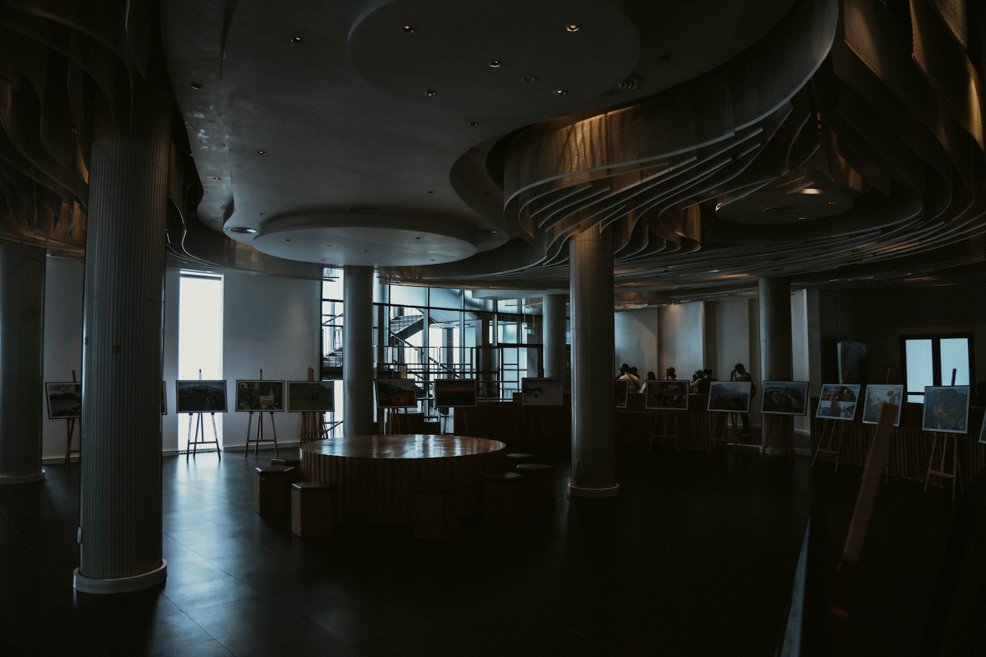 Visitatori passeggiano tra dipinti su cavalletti all'interno di una grande galleria.