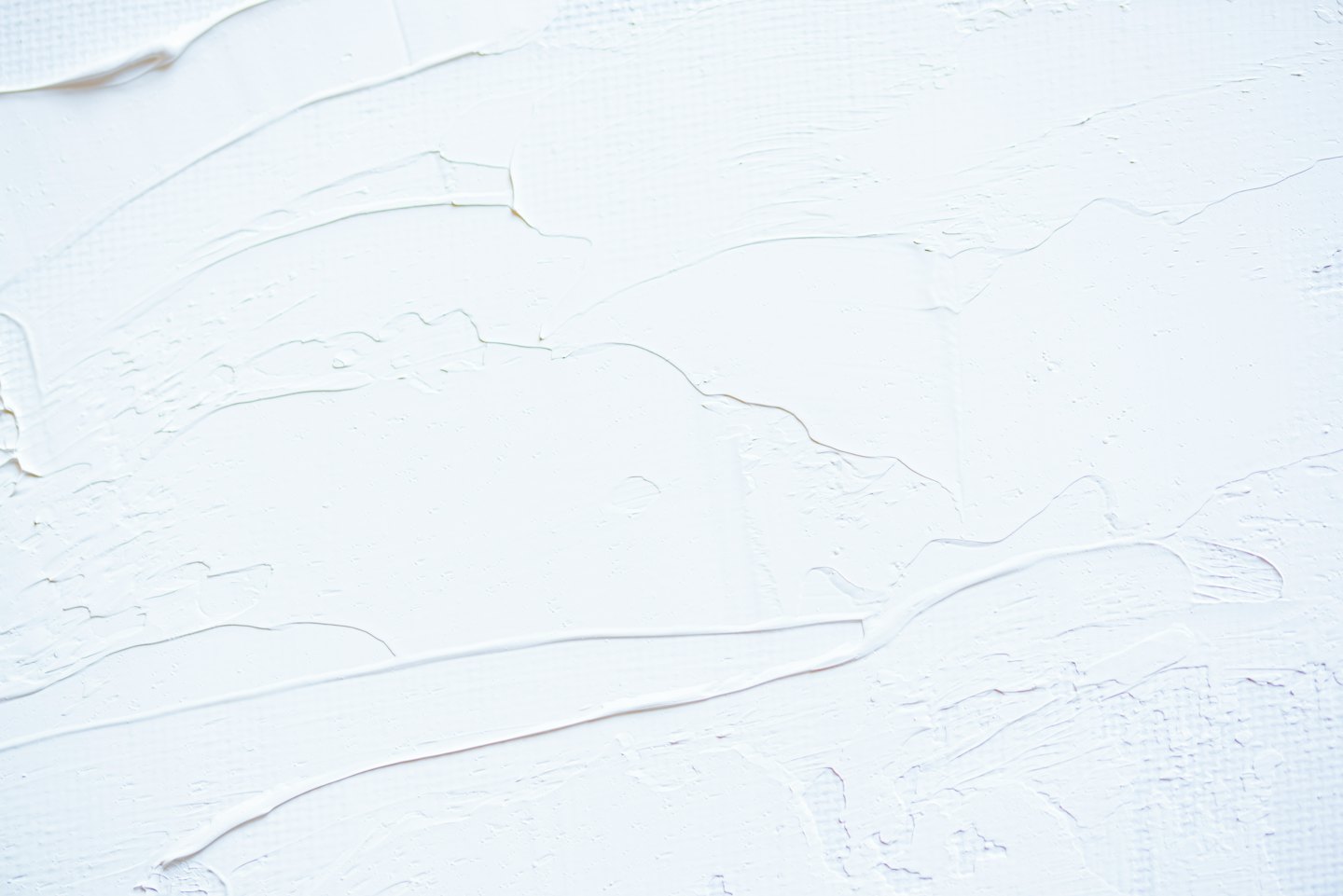 Superficie di gesso bianco testurizzato con sottili motivi a pennellate.