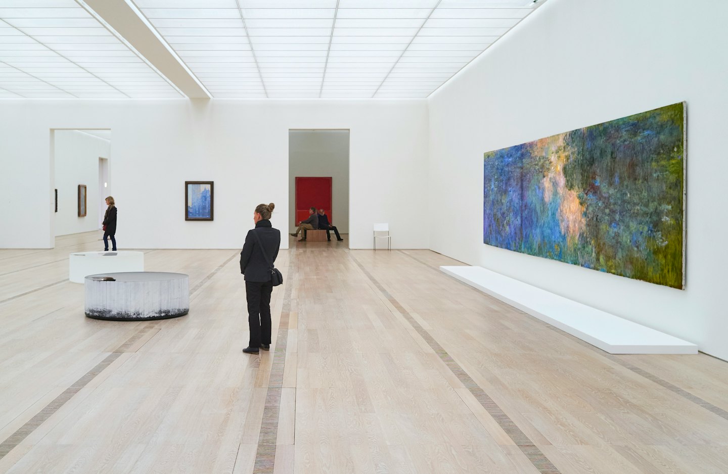 Persona studia un grande quadro astratto in una galleria d'arte moderna.