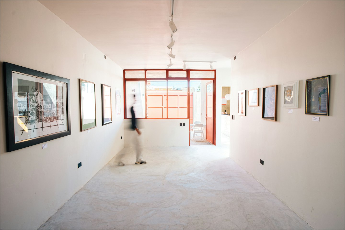 Persona che cammina in una galleria d'arte moderna con opere incorniciate.