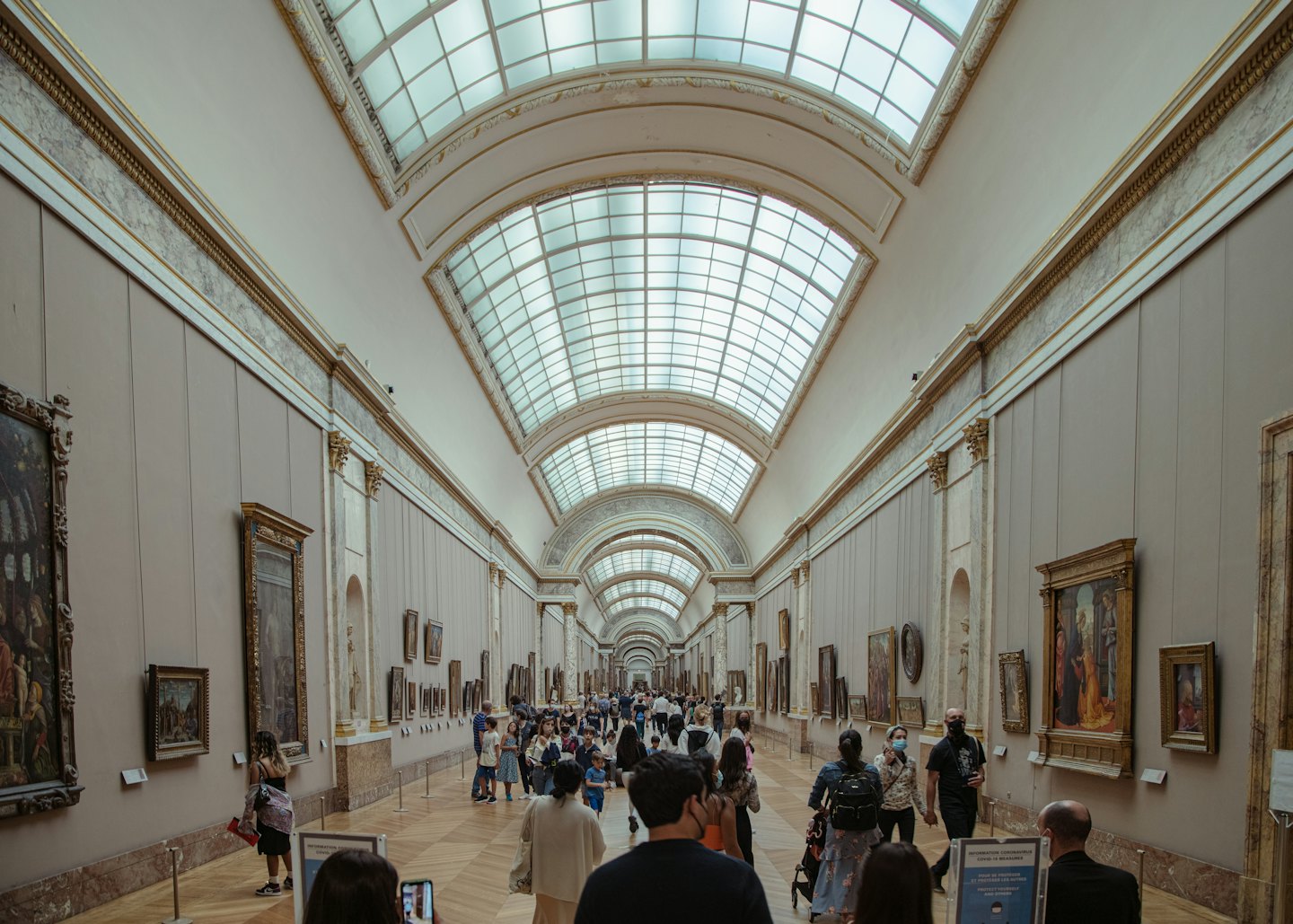 Visitatori passeggiano in una luminosa galleria d'arte con quadri alle pareti.