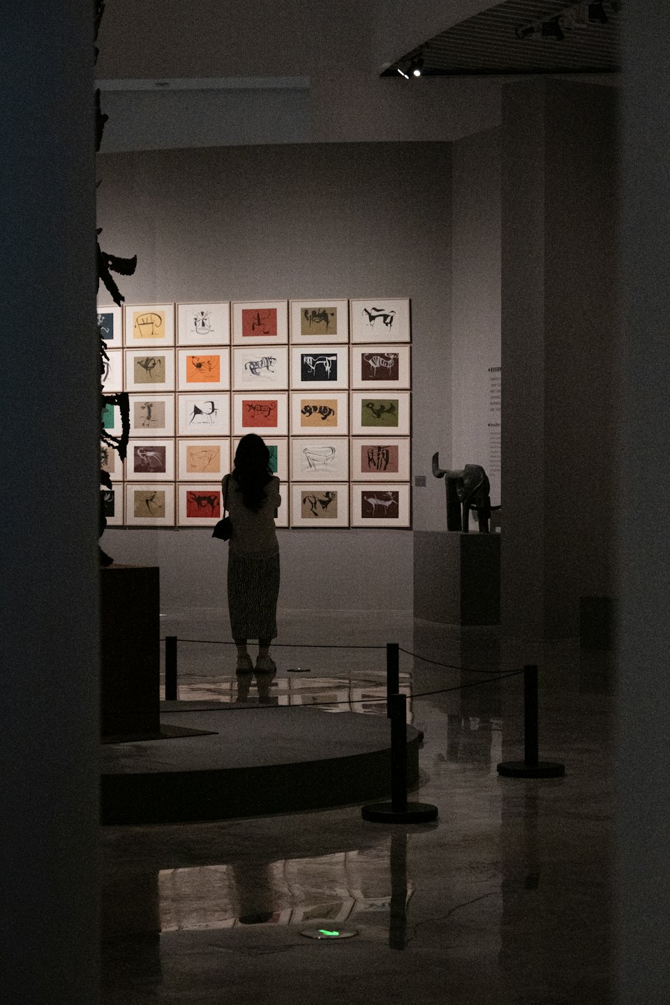 Un visitatore della galleria esamina stampe incorniciate e una scultura di elefante.