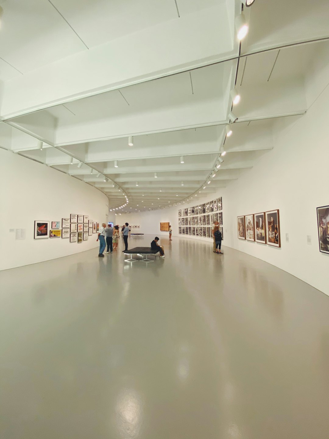 Visitatori esaminano opere d'arte in una galleria moderna e luminosa.