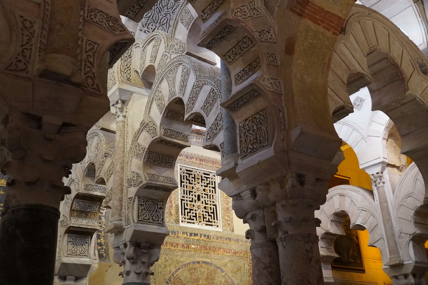 Intricati archi a ferro di cavallo in pietra scolpiti con motivi geometrici e floreali.