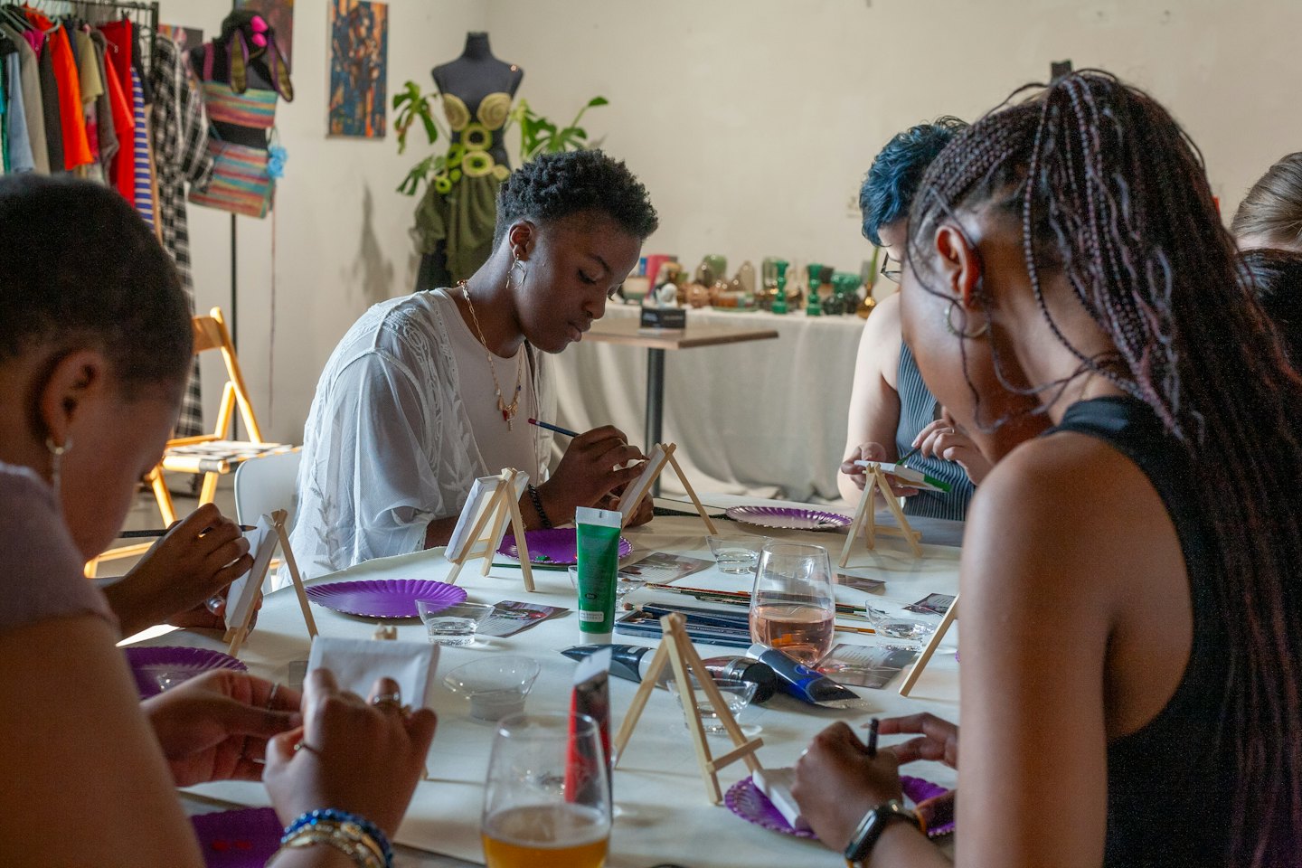 Gruppo eterogeneo di persone che dipingono tele a un tavolo da laboratorio artistico.