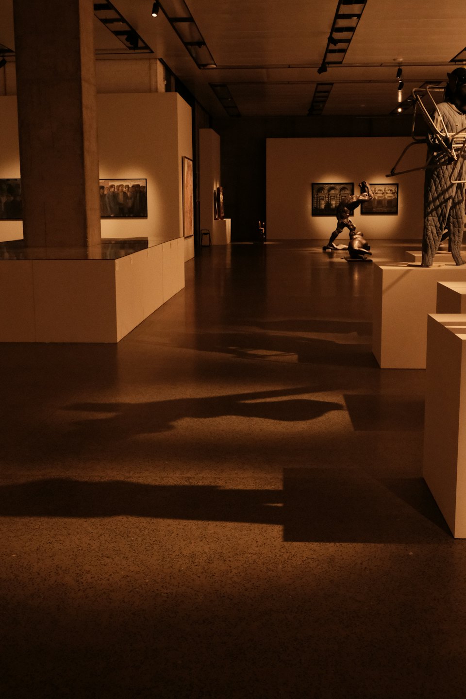 Sala di una galleria d'arte con sculture su piedistalli bianchi.